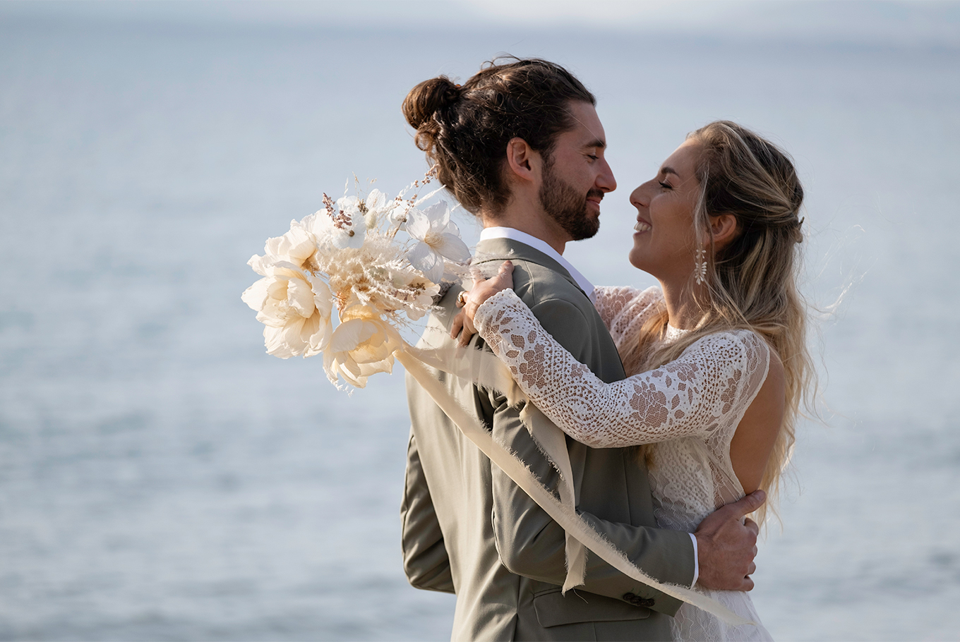 Couple mariés avec bouquet de fleurs en papier blanches et robe blanche costume gris. création Étoile Vagabonde